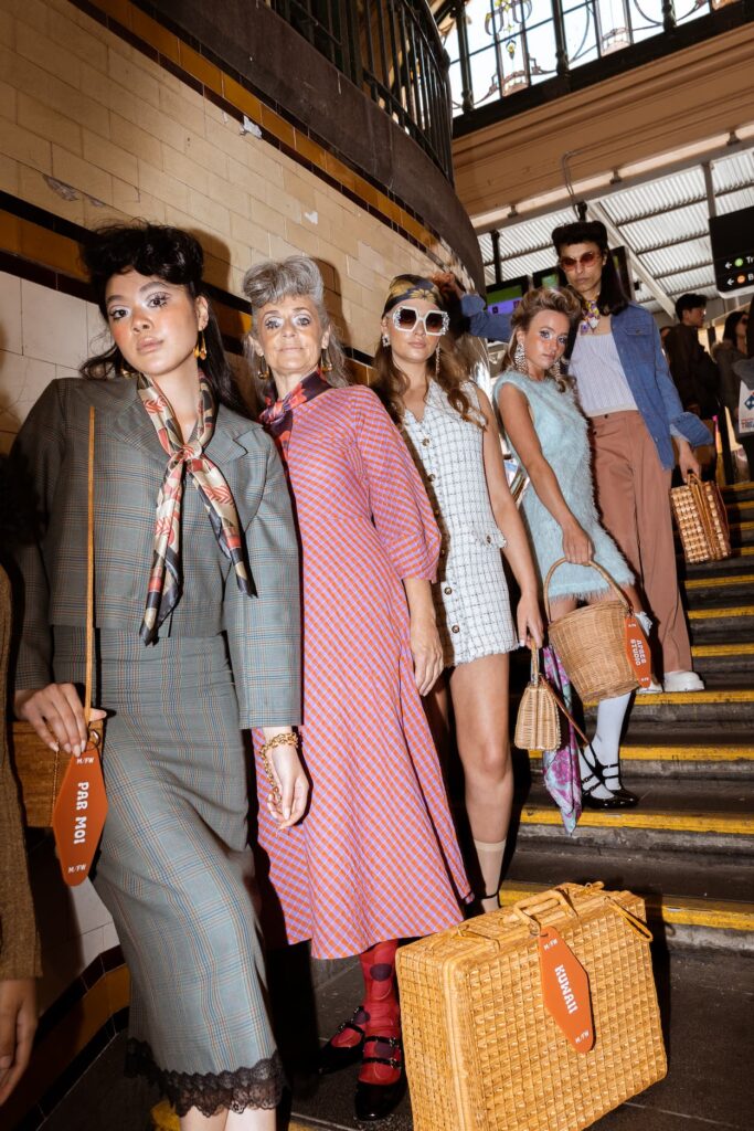 A group of models posing in a line on a subway staircase wearing various Retrospekt Silk Square Scarves for the Retro Boulevard Runway of Melbourne Fashion Week.